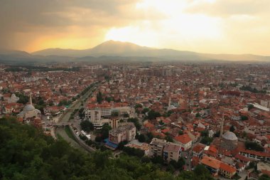 Prizren Kalesi 'nden gün batımından önce eski Prizren kasabasına bakan altın ışık bulutlar arasında parıldıyor, Prizren, Kosova 2022