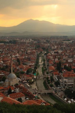 Prizren Kalesi 'nden Bistrica Nehri' ne ve eski Prizren kasabasına gün batımından önce altın güneş ışığı bulutlu gökyüzü Prizren, Kosova 2022 'de doğuyor.