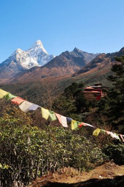 Önünde dua bayrağı olan Tengboche köyünün manastırına bakın ve arka planda Ama Dablam Dağı zirvesi, Everest Ana Kamp Trek, EBC, Nepal 2022