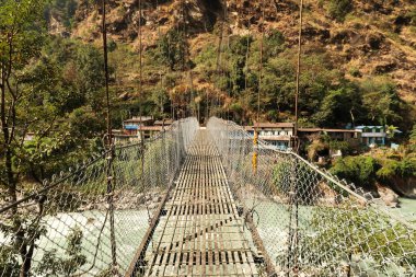 Marsyangdi Nehri 'nden geçip Annapurna Circuit Trek, Nepal 2022' deki Syanche köyüne giden metal asma köprüyü geçiyoruz.