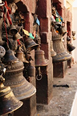 Farklı boyutlarda ve asma kilitlerde birçok metal çan Kathmandu, Nepal 2022 'deki Boudhinath Stupa' nın dış duvarlarından birine bağlıdır.