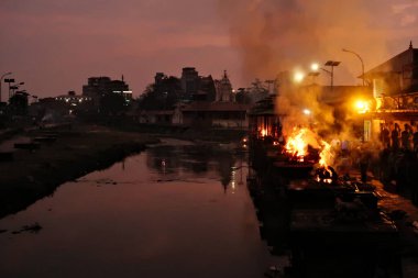 Geleneksel yakma töreninin alevleri Bagmati Nehri kıyısında Pashupatinath Tapınağı Kompleksi, Katmandu, Nepal 2022