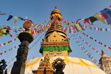 The Swayambhunath Stupa, Temple at golden hour, the golden top is painted with a face and decorated with many colorful prayer flags dancing in the wind, Kathmandu, Nepal 2022