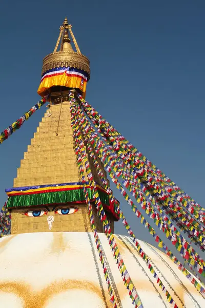 stock image The top, upper part of the Boudhanath Stupa, a golden face surrounded by many colorful prayer flags are attached to it, Kathmandu, Nepal 2022