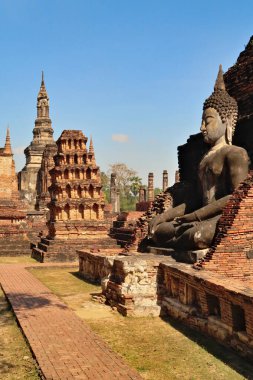 Wat Mahathat Tapınağı 'ndaki büyük Buda heykeli. Arka planda birçok çit, stupa, tarihi park, arkeolojik alan, antik Sukhothai kalıntıları, Tayland 2023.