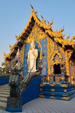 Mavi Tapınağın arka cephesindeki beyaz, ayakta duran Buda heykeline bakın, Wat Rong Suea 10, Chiang Rai Tayland 2023