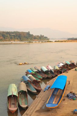 View onto many colorful, traditional, wooden boats docked at the shore of the Mekong River, Wiang Chiang Kong, Thailand 2023 clipart