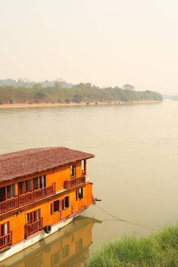 Mekong Nehri 'ni bir yolcu teknesiyle, Mekong Nehri' ne giden bir gemi ön planda demirli Wiang Chiang Kong, Tayland 2023