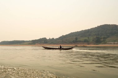 View from the slow boat from Thailand to Laos onto a small boat with two locals on the Mekong River, Laos 2023 clipart