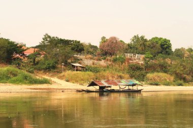 View from the slow boat from Thailand to Laos onto the shore of the Mekong River with a docked river boat, Laos 2023 clipart