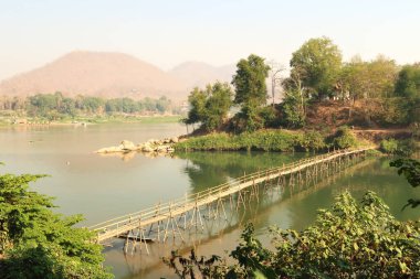 Eski kasabadan Nam Khan Nehri üzerindeki geleneksel bambu köprüsünün arka planda Mekong Nehri, Luang Prabang, Laos 2023