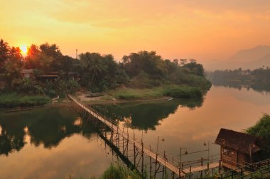 Spectacular view on a traditional bamboo bridge over the Nam Khan River at golden hour, sunset, Luang Prabang, Laos 2023 clipart