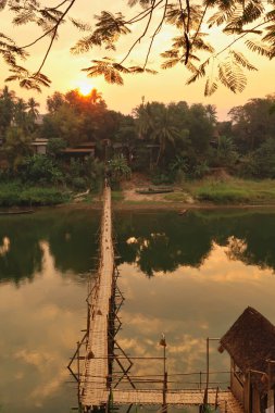 Gün batımında Nam Khan Nehri üzerindeki geleneksel bambu köprüsüne bakın, altın saat, Luang Prabang, Laos 2023