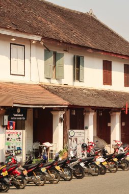 Birçok motosiklet, eski şehir Luang Prabang, Laos 2023 'teki geleneksel bir sömürge evinin önüne park edilmiştir.