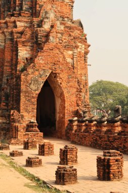 Bir kapı, Wat Chaiwatthanaram Tapınağı, Ayutthaya Tarih Parkı, Tayland 2023 'te oturan uzun bir sıra taş bütçenin yanındaki kapı.