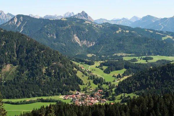 Küçük bir köy olan Unterjoch kasabasına bakın, ormanlar arasında bir vadiye kurulmuş, arka planda dağlardan oluşan Allgaeu, Allgovia, Baravia, Almanya 2023