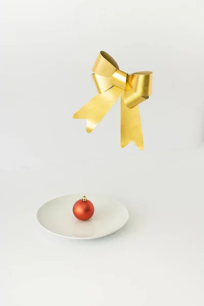 Rode Kerstbal Decoratie Witte Plaat Met Gouden Strik Zweven Boven — Stockfoto