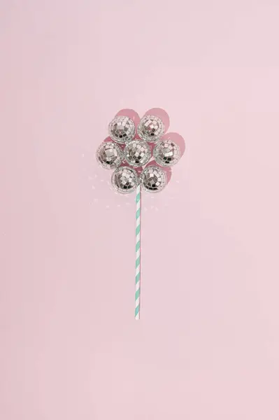 Shiny flower made with disco balls and paper straw. Minimal party concept. Flat lay. Top view.
