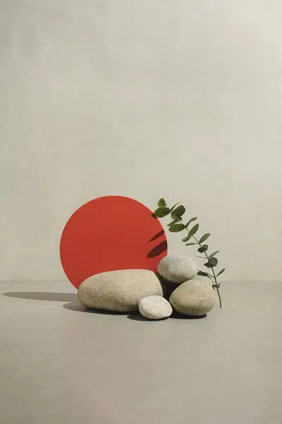 Minimal spa and zen background with red circle, natural stones and eucalyptus branch. Showcase, display case.