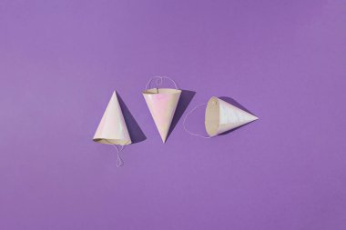 Mor arka planda üç tane kağıt doğum günü partisi şapkası. Asgari konsept.