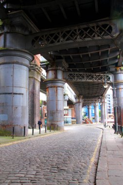Eski metal bir köprünün altındaki taş bir caddenin yaya manzarası