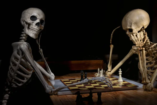 国际象棋游戏是由两个万圣节骷髅放在木桌上制作的 — 图库照片