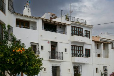 Editör Altea, İspanya - 01 Şubat 2025: İspanya 'nın Valencia bölgesindeki Altea kasabasında beyazlatılmış evler ve bir portakal ağacı