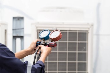 Teknisyen klimayı kontrol ediyor, klimaları doldurmak için ekipmanları ölçüyor..
