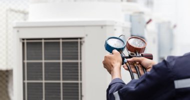 Teknisyen klimayı kontrol ediyor, klimaları doldurmak için ekipmanları ölçüyor..