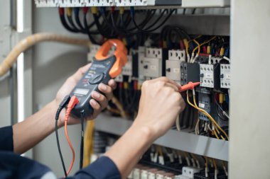 Elektrik mühendisi elektrik kabinesi kontrolündeki voltaj ve elektrik akımını ölçen bir testçi, elektrik sisteminin işleyişini konsept olarak kontrol ediyor .