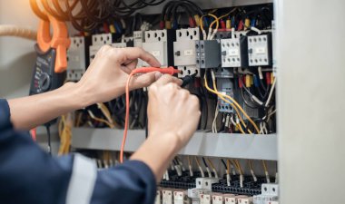 Elektrik mühendisi elektrik kabinesi kontrolündeki voltaj ve elektrik akımını ölçen bir testçi, elektrik sisteminin işleyişini konsept olarak kontrol ediyor .