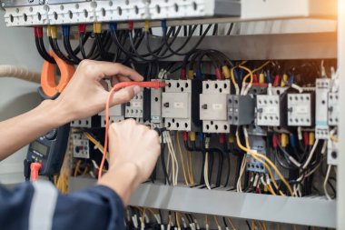 Elektrik mühendisi elektrik kabinesi kontrolündeki voltaj ve elektrik akımını ölçen bir testçi, elektrik sisteminin işleyişini konsept olarak kontrol ediyor .