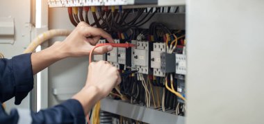 Elektrik mühendisi elektrik kabinesi kontrolündeki voltaj ve elektrik akımını ölçen bir testçi, elektrik sisteminin işleyişini konsept olarak kontrol ediyor .