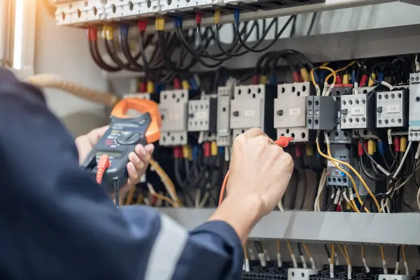 Elektrik mühendisi elektrik kabinesi kontrolündeki voltaj ve elektrik akımını ölçen bir testçi, elektrik sisteminin işleyişini konsept olarak kontrol ediyor .