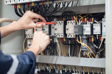 Elektrik mühendisi elektrik kabinesi kontrolündeki voltaj ve elektrik akımını ölçen bir testçi, elektrik sisteminin işleyişini konsept olarak kontrol ediyor .