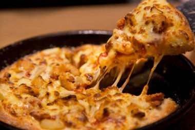 İtalyan pizzasının içinde, masada erimiş peynirli sıcak pizza dilimi..