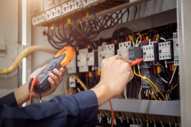 Elektrik mühendisi, devre kesici ve kablo tesisat sistemindeki elektrik akımını kontrol etmek için ölçüm ekipmanı kullanıyor. .