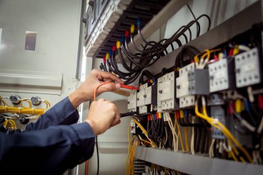Elektrik mühendisi, devre kesici ve kablo tesisat sistemindeki elektrik akımını kontrol etmek için ölçüm ekipmanı kullanıyor. .