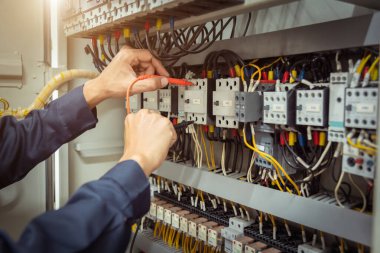 Elektrik mühendisi, devre kesici ve kablo tesisat sistemindeki elektrik akımını kontrol etmek için ölçüm ekipmanı kullanıyor. .