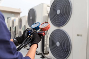 Teknisyen klimayı kontrol ediyor, klimaları doldurmak için ekipmanları ölçüyor..