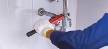 Tesisatçı ayarlanabilir anahtarla beyaz lavabo borusunu tamir ediyor..