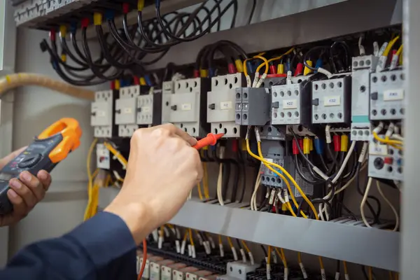 Elektrik mühendisi, devre kesici ve kablo tesisat sistemindeki elektrik akımını kontrol etmek için ölçüm ekipmanı kullanıyor. .