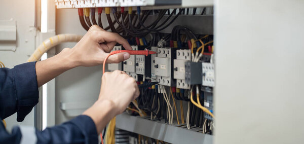 Инженер-электрик работает тестером измерения напряжения и тока электрической линии в электрическом шкафу управления, концепция проверки работы электрической системы .