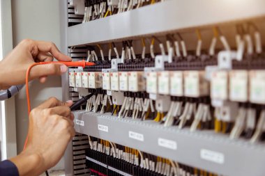 Elektrik mühendisi, devre kesici ve kablo tesisat sistemindeki elektrik akımını kontrol etmek için ölçüm ekipmanı kullanıyor. .