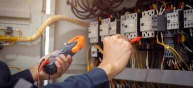 Elektrik mühendisi, devre kesici ve kablo tesisat sistemindeki elektrik akımını kontrol etmek için ölçüm ekipmanı kullanıyor. .