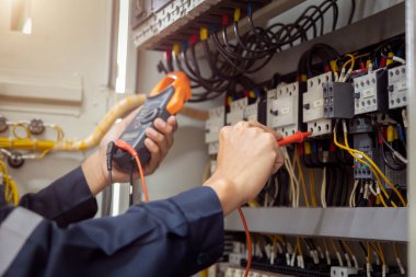 Elektrik mühendisi, devre kesici ve kablo tesisat sistemindeki elektrik akımını kontrol etmek için ölçüm ekipmanı kullanıyor. .