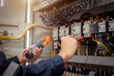 Elektrik mühendisi, devre kesici ve kablo tesisat sistemindeki elektrik akımını kontrol etmek için ölçüm ekipmanı kullanıyor. .