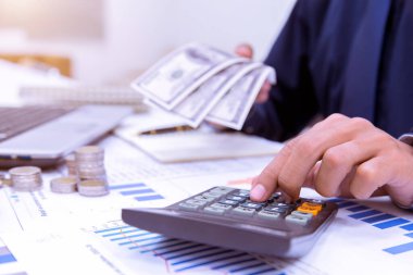 Ofisteki hesap makinesiyle iş adamının elleri ve ofisteki masada sayılan mali verileri analiz etmek..