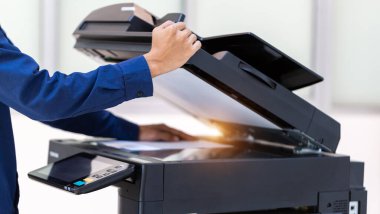 İşadamı, yazıcı fotokopi ağı panelindeki düğmeye basar, ofis konseptinde fotokopi üzerinde çalışır, yazıcı, kağıt tarama ve kopyalama için ofis çalışanı ekipmanıdır.