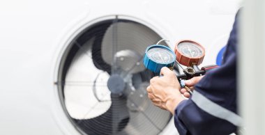 Teknisyen klimayı kontrol ediyor, klimaları doldurmak için ekipmanları ölçüyor..